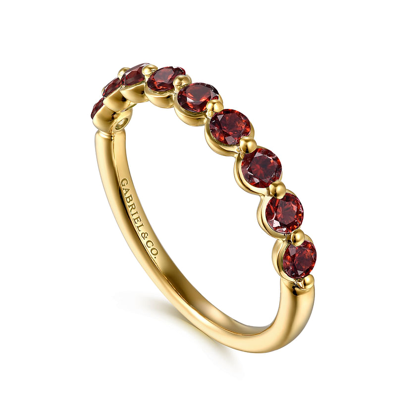 The Gabriel & Co 14K Yellow Gold Garnet Stackable Ring features a row of round garnets along the band and "Gabriel & Co" engraved inside.