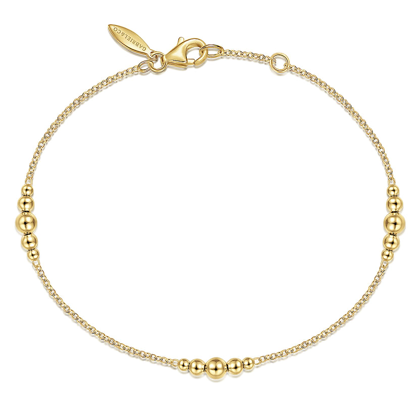 The Gabriel & Co 14K Yellow Gold Graduating Bead Stations Bracelet features evenly spaced gold beads on a delicate chain with a lobster clasp closure and small tag.