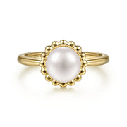 The Gabriel & Co 14K Yellow Gold Pearl Ring showcases a central round white pearl, surrounded by a decorative beaded halo and set against a white background.