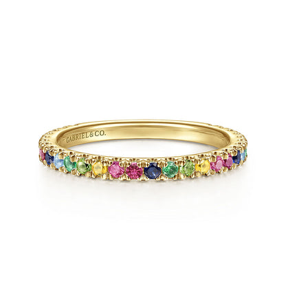 The 14K Yellow Gold Rainbow Color Stone Stackable Ring by Gabriel & Co features a thin band set with small, round blue, green, yellow, and pink gemstones all around, plus an inner engraving of “GABRIEL & CO.”.