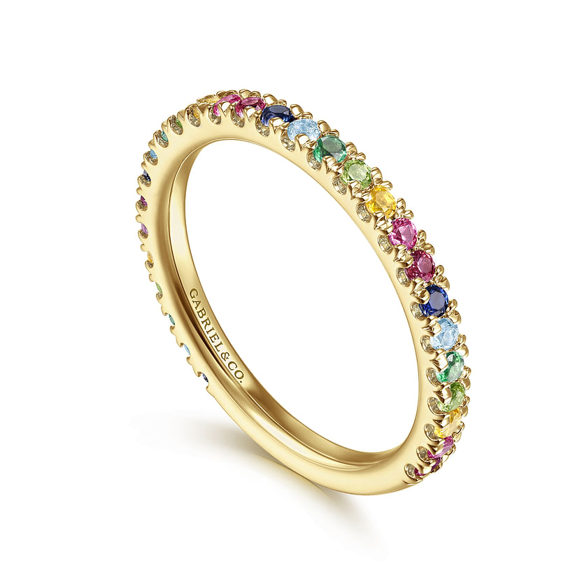 The Gabriel & Co 14K Yellow Gold Rainbow Color Stone Stackable Ring features a slim band set with round pink, blue, green, and yellow stones. "CARAT & CO." is engraved inside—perfect for stacking in vibrant style.