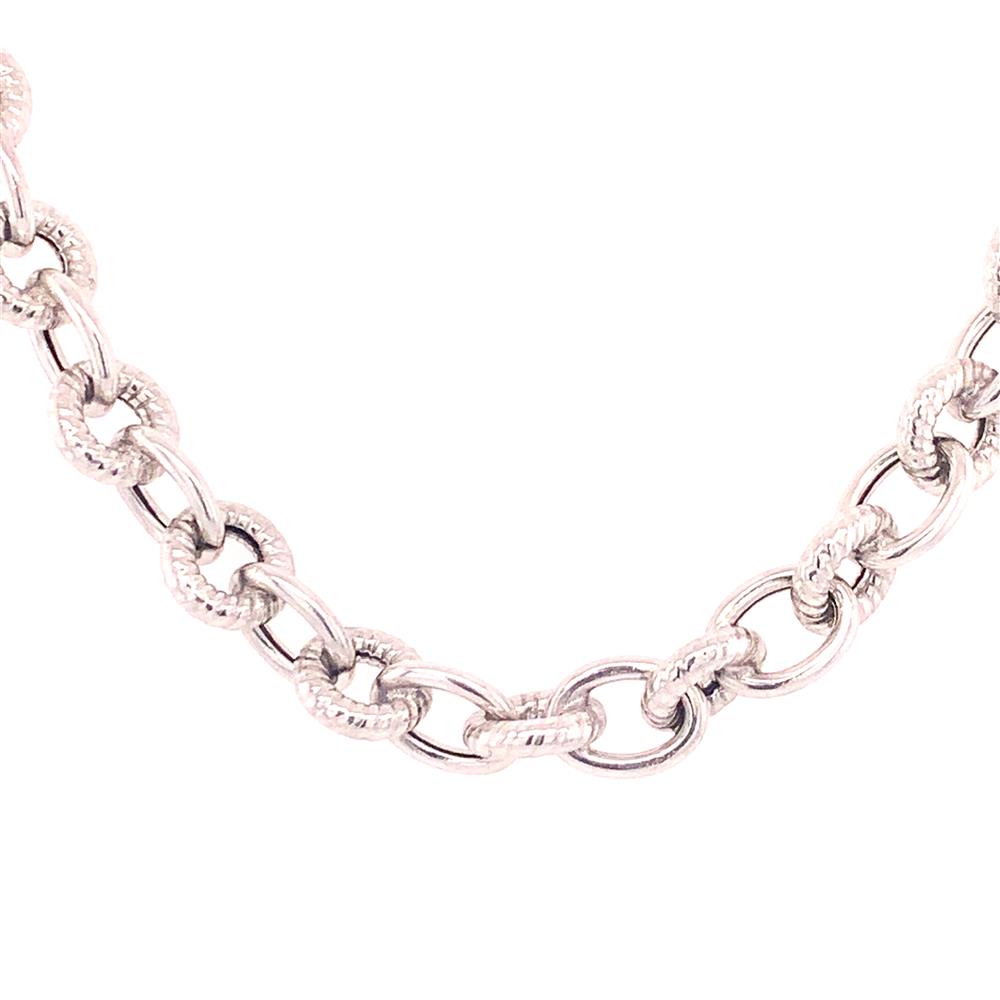 Close-up of the Sterling Silver Textured Rolo Chain by Royal Chain Group-Royal Chain, showcasing interlocked oval links. The textured pattern on the surface of each link gives the chain its distinctive, intricate appearance. The white background accentuates the design of this Royal Chain product.