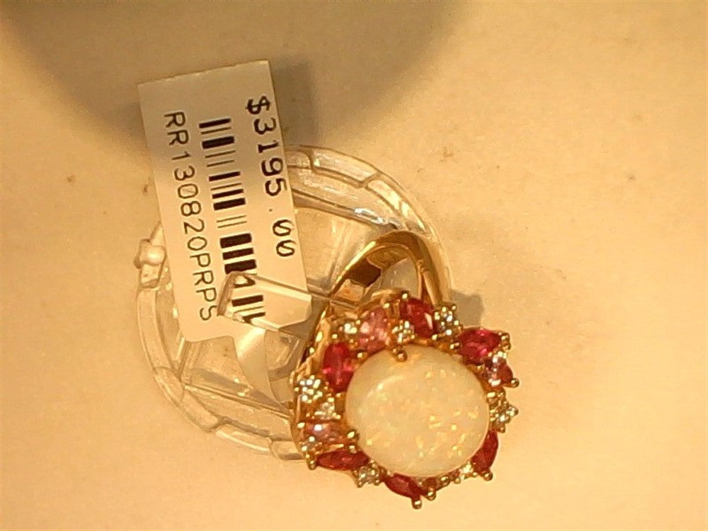 A 14k rose gold Opal, Pink Sapphire, Ruby, and Diamond ring (size 6.75) by Ryan Gems sits on a light background with a price tag of $3195.00 and product code attached. Central opal is accented by rubies and clear stones.