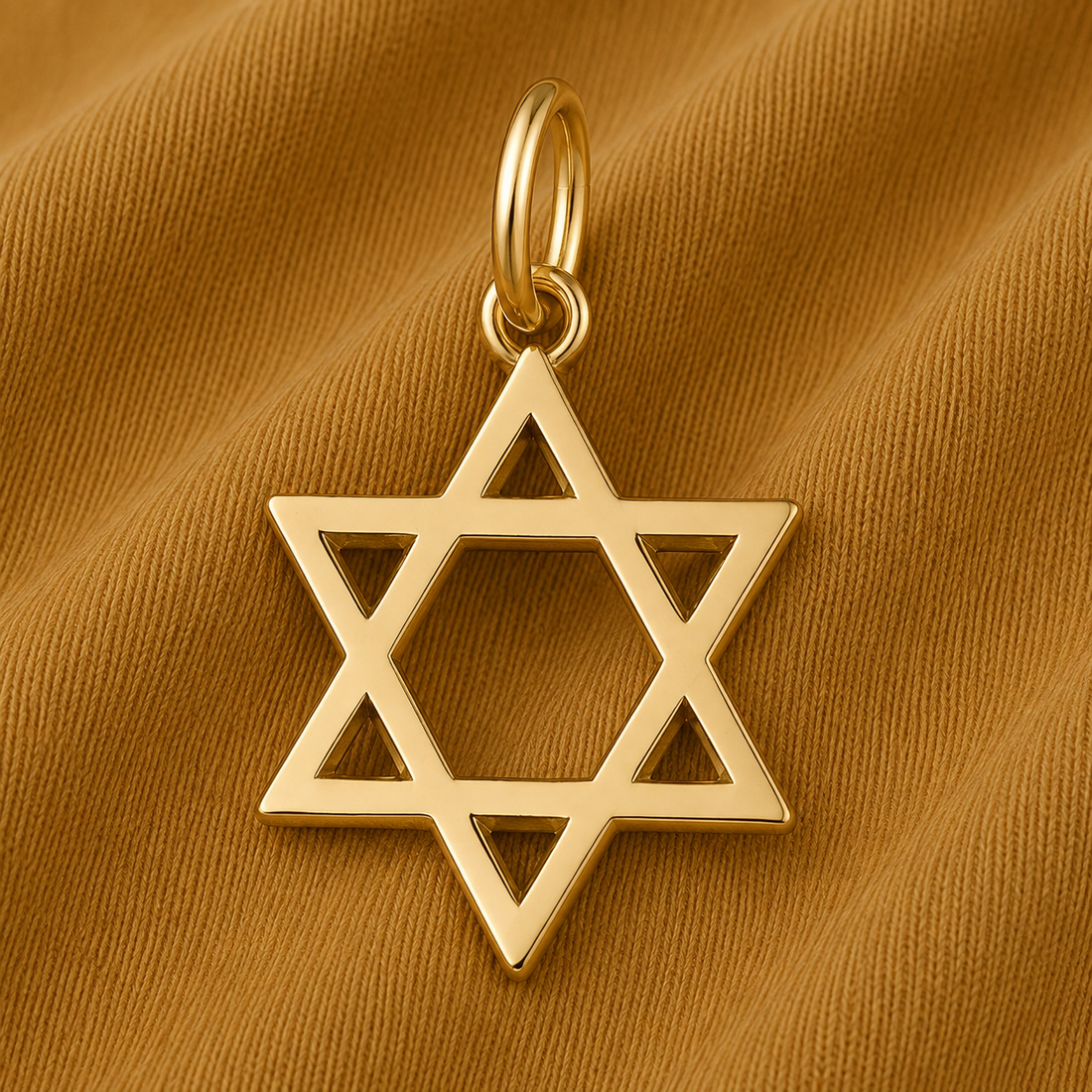 A Rembrandt Charms Star of David Charm- Gold Plated pendant rests on a textured brown fabric background, elegantly highlighting this classic piece of Jewish jewelry and celebrating the timeless symbol of Judaism.