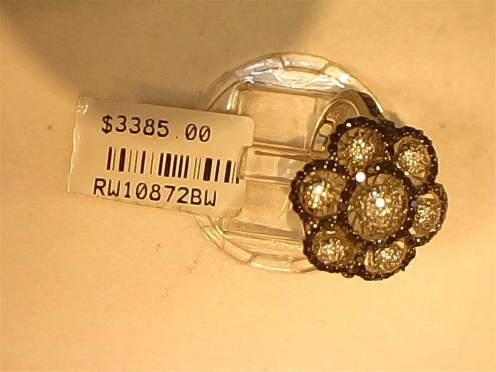 A Ryan Gems Black and White Diamond Flower Ring in 14k white gold, size 7, is displayed on a transparent stand with a $3385.00 price tag and code RW10872BW.