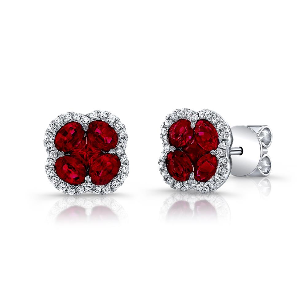 The 18K White Gold Clover Shaped Ruby and Diamond Outline Stud Earrings by Uneek Jewelry boast an elegant design with a four-petaled flower-like shape, featuring vibrant red rubies at the center and surrounded by a halo of sparkling clear diamonds. The earrings are set in 18K white gold and feature a push-back closure.