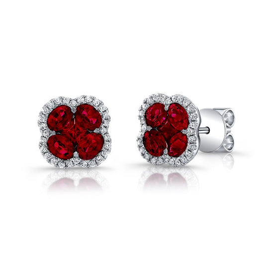 The 18K White Gold Clover Shaped Ruby and Diamond Outline Stud Earrings by Uneek Jewelry boast an elegant design with a four-petaled flower-like shape, featuring vibrant red rubies at the center and surrounded by a halo of sparkling clear diamonds. The earrings are set in 18K white gold and feature a push-back closure.