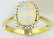 Introducing the Bellarri Faceted Opal and Diamond Ring from the Forever Young Collection: a stunning gold ring featuring a large, rectangular cushion-cut opal gemstone with 1.33 carats, surrounded by a dazzling halo of 0.17 carats of small diamonds. The opal exhibits an enchanting play of colors with vibrant flashes of green, orange, and yellow. The polished 14K yellow gold band completes this captivating piece.