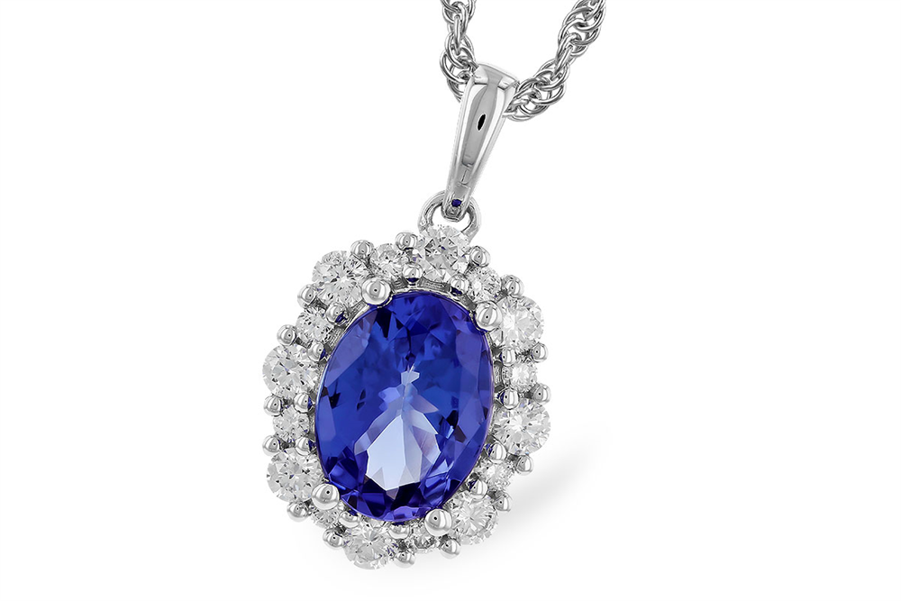This Tanzanite and Diamonds 14K White Gold Necklace by Allison Kaufman features a stunning 1.02-carat oval tanzanite encircled by small, clear round stones. The pendant is suspended from a 14K white gold chain, highlighting the intricate metalwork surrounding the stone. The vibrant blue of the tanzanite contrasts beautifully with the sparkling stones and elegant setting.