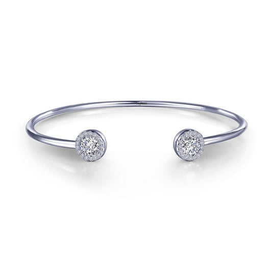 The Open Cuff Halo Bracelet by Lafonn showcases a minimalist design with a sleek, silver band and two round diamond-encrusted ends. This bracelet exudes modern elegance and luxury with its polished finish and refined appearance.