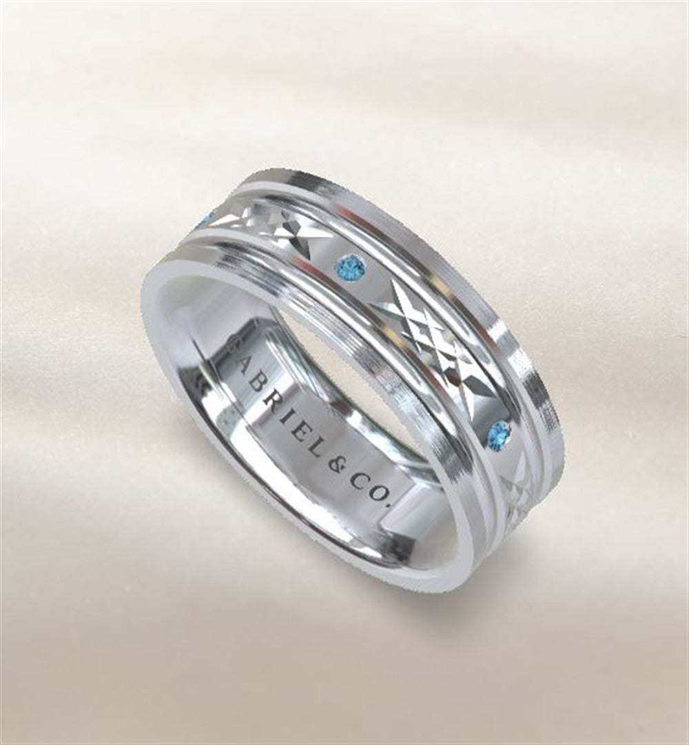 The Gabriel & Co mens silver and blue topaz ring features engraved geometric patterns and blue gemstones, with "GABRIEL & CO." inscribed inside. This stylish accessory is set against a soft, light beige background.