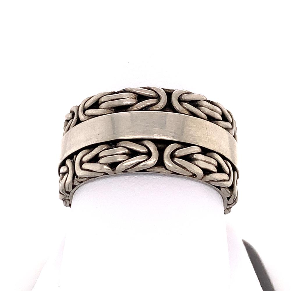 The Lois Hill Gents Sterling Silver Ring / S features a chunky design with an intricate braided pattern on both the top and bottom. The smooth, polished center band offers a striking contrast to the detailed craftsmanship. This classic piece of sterling silver jewelry is elegantly displayed on a white stand.