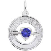 A circular sterling silver charm with "SEPTEMBER" inscribed along the top. Attached to the bottom is an arrow piercing through a heart-shaped blue sapphire, the 09 September birthstone. The 09 September Birthstone Charm in Sterling Silver by Rembrandt Charms features a loop at the top for a chain, perfect for any collection.