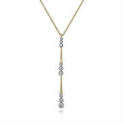 The Gabriel & Co. 14K Yellow Gold Graduated Diamond Station Drop Y Necklace features a delicate design with round white diamonds set in a vertical line in a drop pendant style. The evenly spaced diamonds along the vertical drop create an elegant, modern look, complemented by the fine, simple link chain.