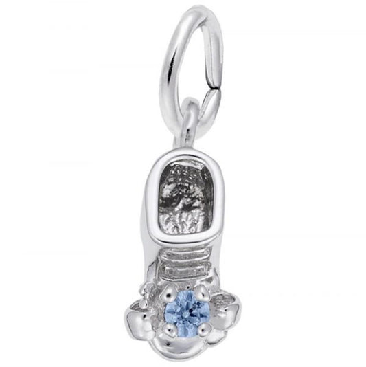 The December Baby Bootie Charm by Rembrandt Charms, crafted in sterling silver, features detailed grooves and patterns adorned with a small blue topaz gemstone at the toe. It includes an attached loop for fastening to a bracelet or necklace.