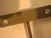 Close-up of Veer’s 14KW 4-prong / 1.25ctw Screw Back Stud, showcasing two sparkling diamond-like crystals mounted at each end in an elegant 4-prong design. The bar is displayed vertically on a stand, with the blurred background highlighting the clarity of the crystals.