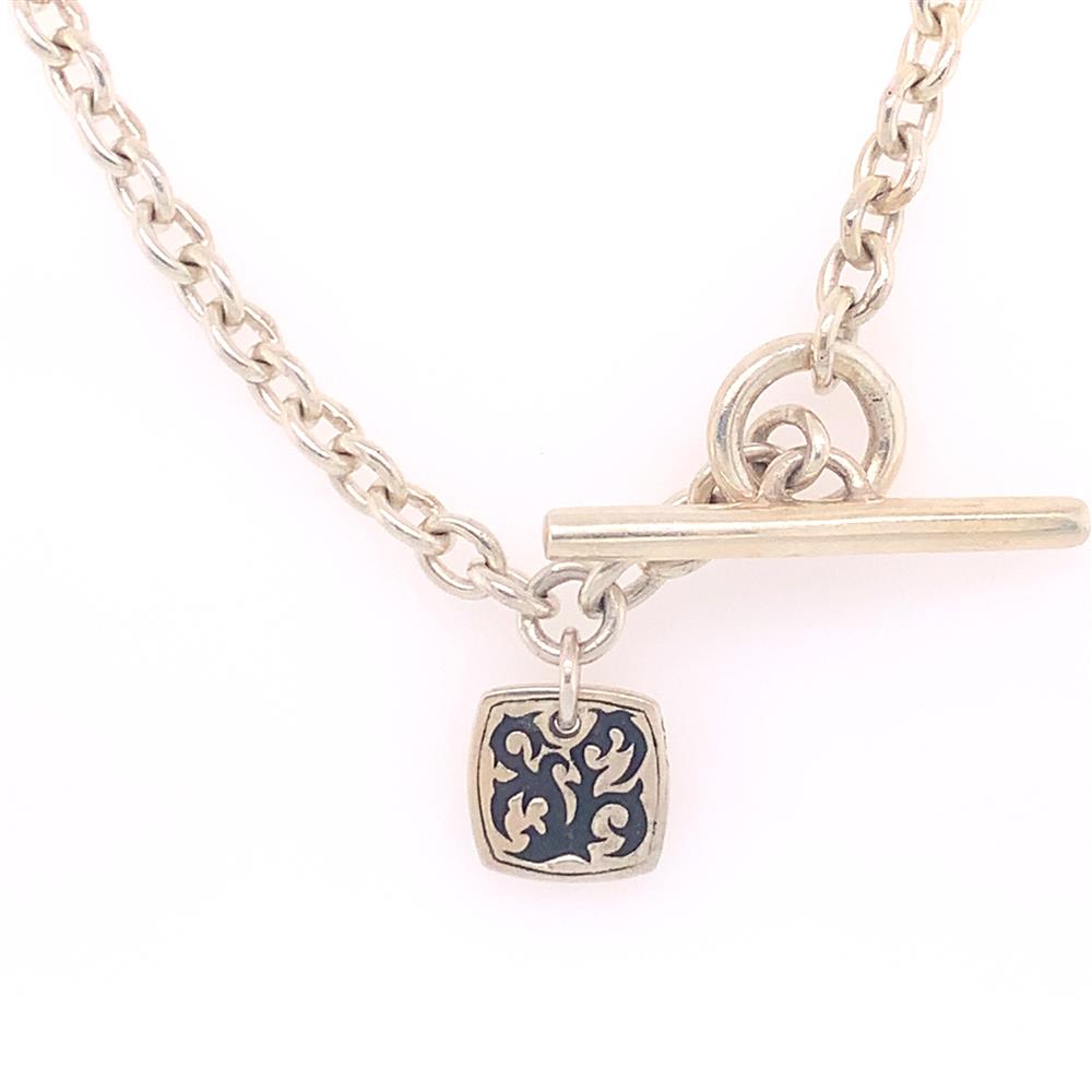 The Gents Sterling Silver Necklace by Lois Hill features a toggle clasp and a small square pendant with an intricate, abstract design in black and silver.