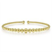 This stunning 14K Yellow Gold Bujukan Open Bangle by Gabriel & Co features a beautiful design of small and large alternating round beads. Presented against a plain white background, this elegant bracelet boasts a minimalist open front design.