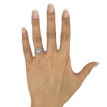 A hand with neatly manicured nails wears the FANA 14K White Gold Cushion Halo Diamond Engagement Ring, featuring a sparkling lab-grown diamond on the ring finger, set against a plain white background.