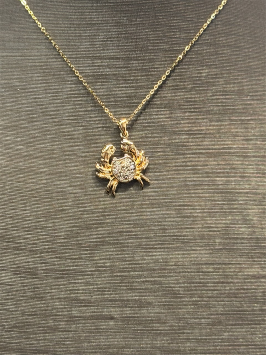 The Ryan Gems Diamond Crab Necklace features a 14k yellow gold chain with a crab-shaped pendant adorned with sparkling stones, elegantly displayed against a textured dark background.