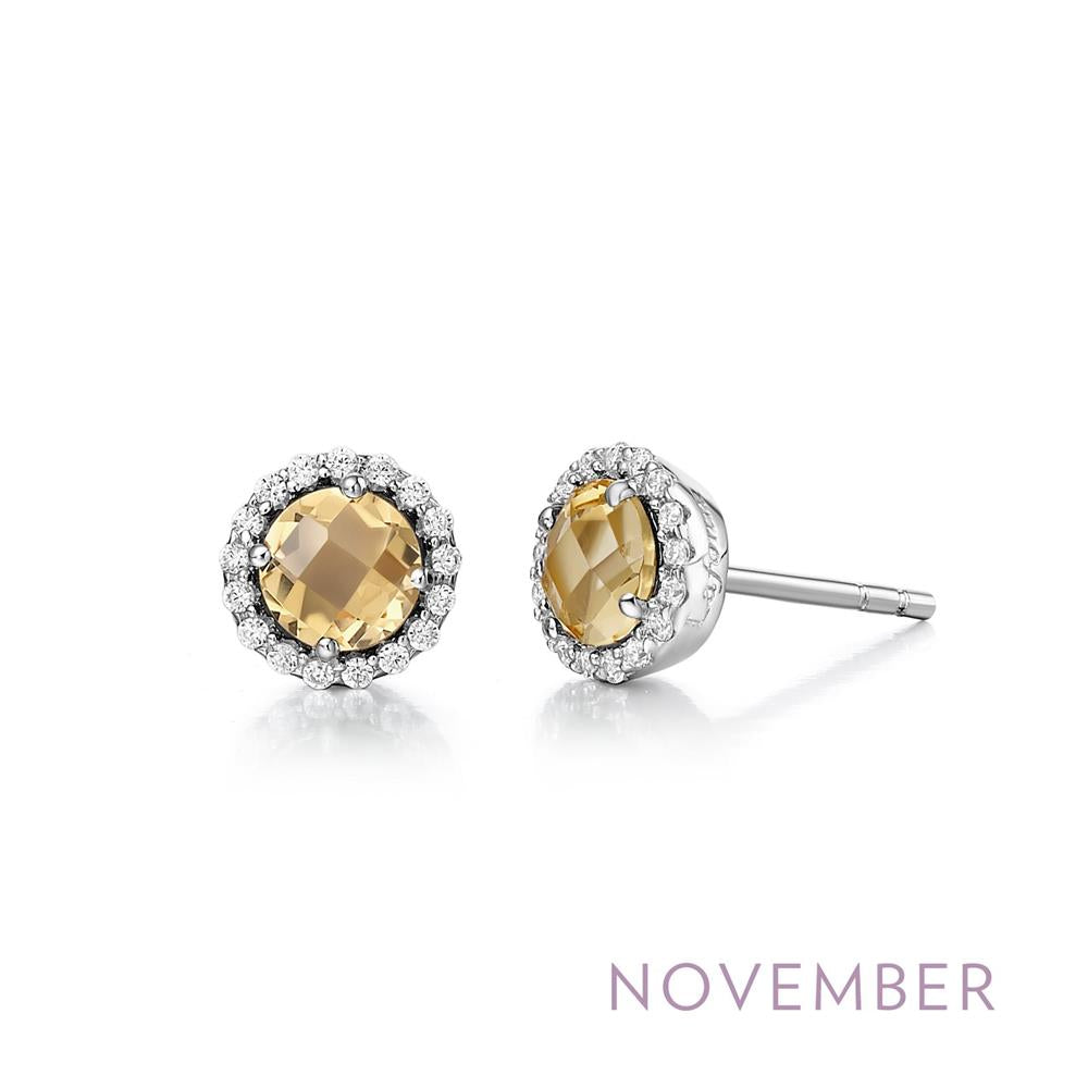A pair of Lafonn's November Birthstone Earrings featuring round, faceted genuine citrines encircled by a halo of small white crystals. The earrings are set in a silver-toned metal, with the word "NOVEMBER" printed below in light purple text to celebrate birthstone jewelry for the month.