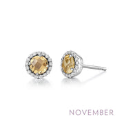 A pair of Lafonn's November Birthstone Earrings featuring round, faceted genuine citrines encircled by a halo of small white crystals. The earrings are set in a silver-toned metal, with the word "NOVEMBER" printed below in light purple text to celebrate birthstone jewelry for the month.