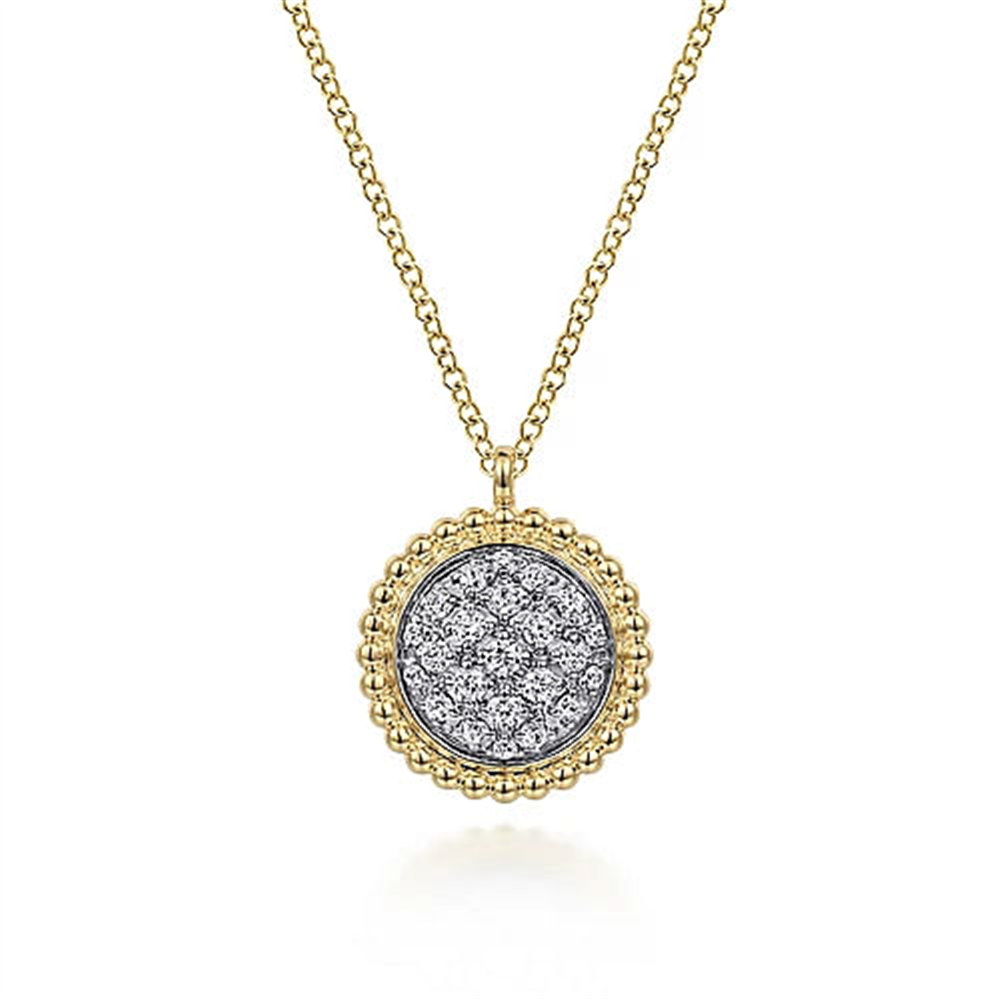 A close-up image of Gabriel & Co's 14K Yellow Gold Bujukan and Diamond Pavé Pendant Necklace. The pendant showcases a central section adorned with numerous small, sparkling diamonds, encircled by an intricate beaded gold border. The simple chain perfectly complements the elegant pendant.