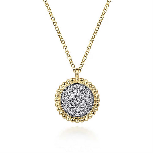 A close-up image of Gabriel & Co's 14K Yellow Gold Bujukan and Diamond Pavé Pendant Necklace. The pendant showcases a central section adorned with numerous small, sparkling diamonds, encircled by an intricate beaded gold border. The simple chain perfectly complements the elegant pendant.