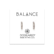 A pair of Dogeared Balance Flat Bar - Earring SS minimalist stud earrings are displayed on a white card with the words "BALANCE" and "DOGEARED MADE IN THE U.S.A." in black text. The card also features a stylized dandelion design.