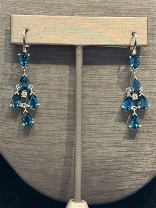 The Ryan Gems Pear Shaped London Blue Topaz Dangles feature three teardrop gems in a triangular design set in 14k white gold, accented with clear stones and displayed on a stand.