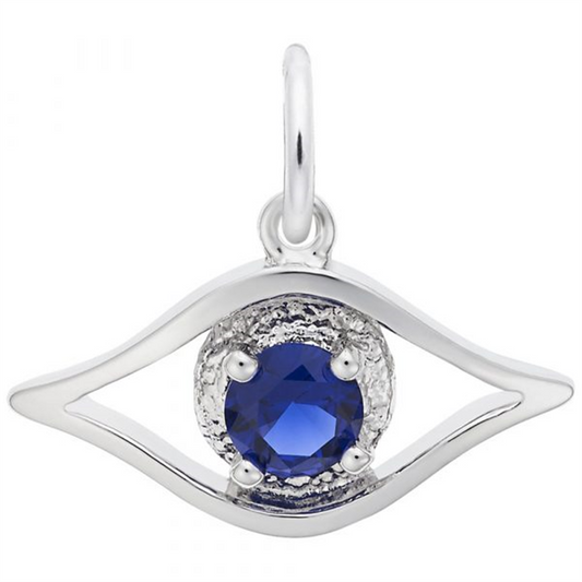 The Rembrandt Charms Evil Eye - Sterling Silver Charm features an enchanting evil eye design with a deep blue gemstone center, encased in a textured silver setting, and includes a metallic loop for easy attachment to a chain.