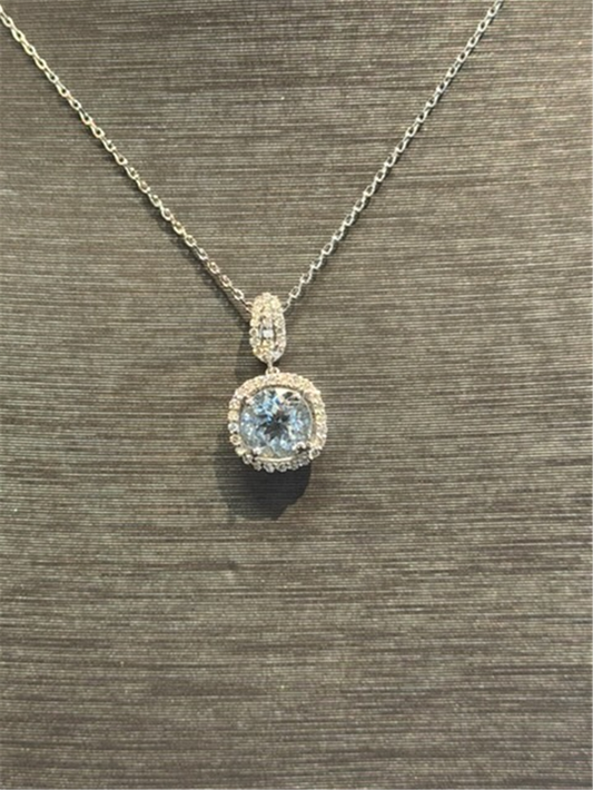 The Ryan Gems Aquamarine and Diamond Pendant in 14k white gold, featuring a round aquamarine surrounded by sparkling diamonds, is shown on a textured gray surface, highlighting its elegant beauty.