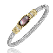 This delicate bracelet from Alwand Vahan Jewelry features a twisted silver band accompanied by a central oval, faceted gemstone in a dark iridescent hue. The gemstone, reminiscent of gray mother of pearl's serene elegance, is set in an ornate gold bezel with intricate detailing on each side. This piece is named the 4MM Closed Band 0.08ct 13.5x7 Barrel Gray Mother of Pearl and comes in Size B2.