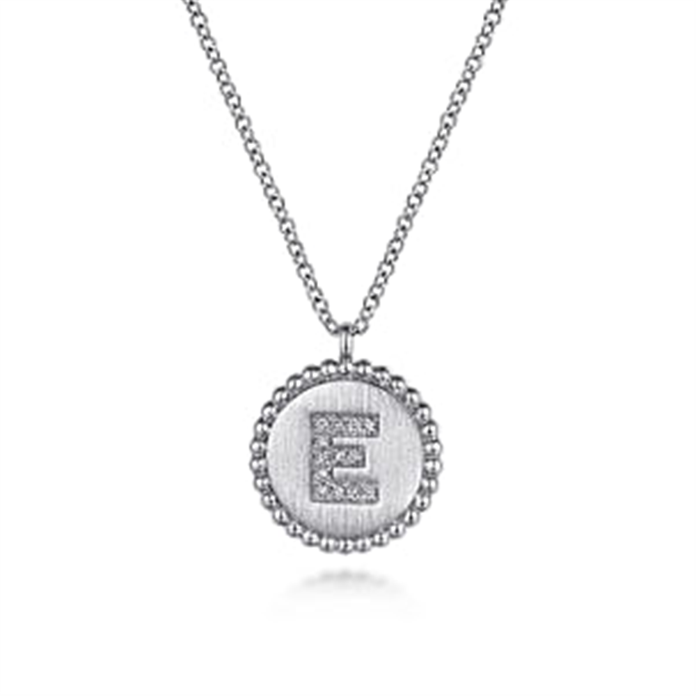 The Gabriel & Co 925 Sterling Silver Diamond Bujukan Initial E Necklace features a round pendant with beaded edges. The pendant showcases a large, capital letter "E" encrusted with small diamonds, set against a textured background. This exquisite initial pendant adds a personal touch to any ensemble.