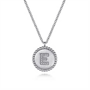 The Gabriel & Co 925 Sterling Silver Diamond Bujukan Initial E Necklace features a round pendant with beaded edges. The pendant showcases a large, capital letter "E" encrusted with small diamonds, set against a textured background. This exquisite initial pendant adds a personal touch to any ensemble.