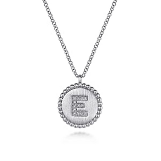 The Gabriel & Co 925 Sterling Silver Diamond Bujukan Initial E Necklace features a round pendant with beaded edges. The pendant showcases a large, capital letter "E" encrusted with small diamonds, set against a textured background. This exquisite initial pendant adds a personal touch to any ensemble.