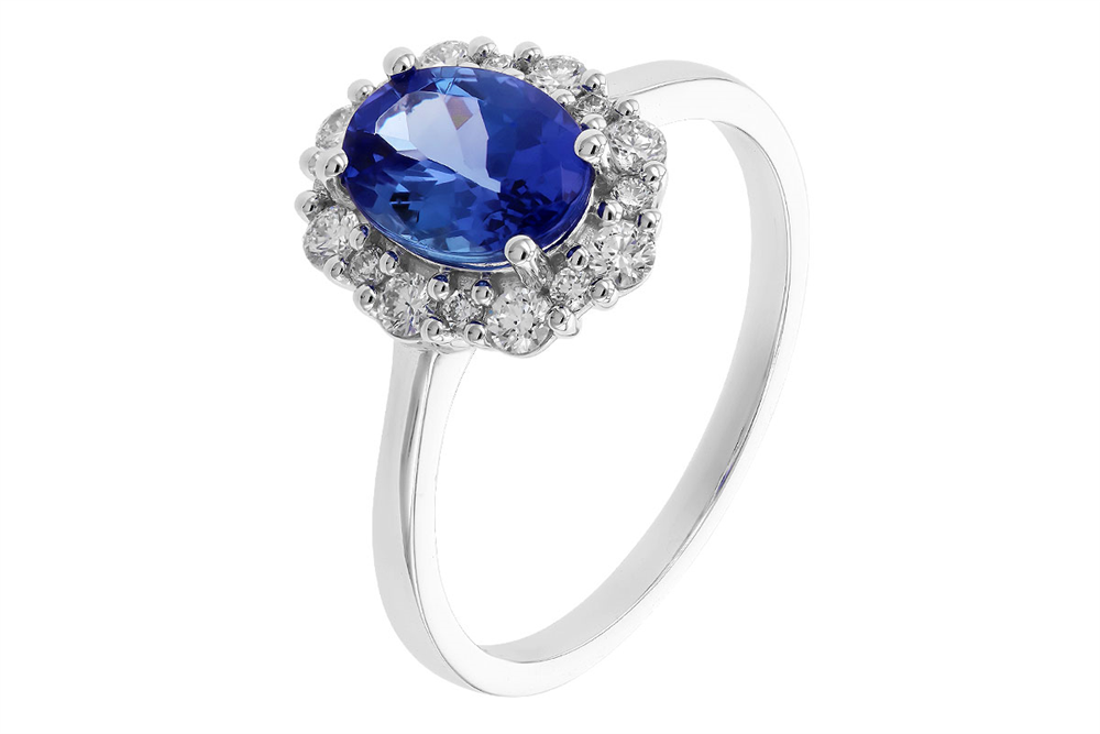 Introducing the Tanzanite and Diamond 14k White Gold Ring by Allison Kaufman: a stunning piece featuring an oval cut tanzanite, elegantly surrounded by a halo of diamond accents. The slender, smooth band enhances the elegance of the central gemstone setting against a plain white background.