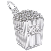 The Rembrandt Charms Popcorn Charm / Sterling Silver is intricately crafted in the shape of a popcorn box, complete with individual popcorn kernels at the top and vertical stripes on the sides. The front of this charming piece features the word "POPCORN" in raised text and has a loop at the top for easy attachment to a chain or bracelet.