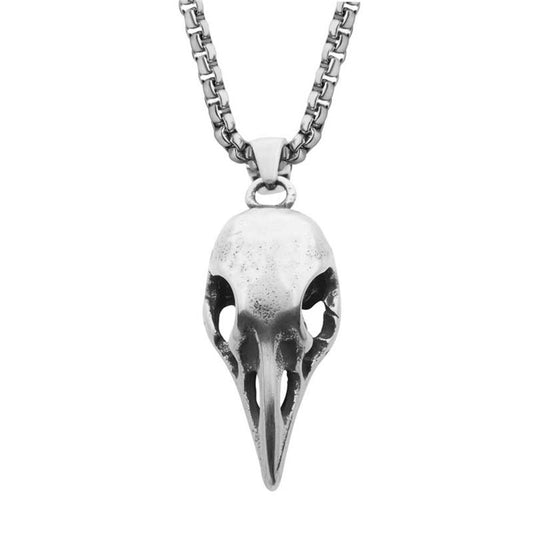 The Distressed Matte Steel Crow Skull Pendant with Chain from INOX features a detailed carving of a crow skull with hollow eye sockets, hanging elegantly from a bold box chain. Its gothic and artistic design makes it a striking piece.