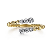 The 14K White-Yellow Gold Bujukan Ball and Diamond Open Bypass Ring from Gabriel & Co showcases a stunning design featuring two open ends. Each end is adorned with a cluster of small round diamonds, which create a sparkling accent. This elegant piece from the Gabriel & Co Bujukan Collection blends contemporary elements with luxurious materials, offering an exquisite appearance.
