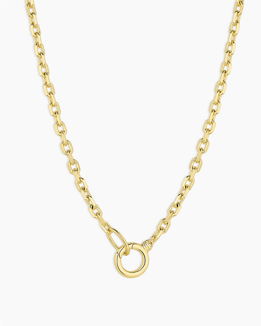 The Asher Necklace by Gorjana is a long, 18k gold plated piece with medium oval links and a central round ring pendant, shown on a white background.