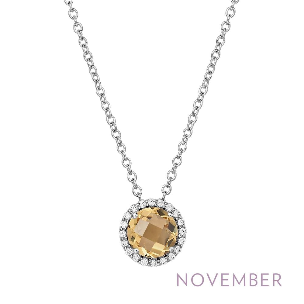 The "November Birthstone Necklace" by Lafonn showcases a stunning round yellow gemstone, symbolizing the November birthstone, encircled by sparkling clear stones. This elegant pendant is suspended from a delicate silver chain. The word "November" is highlighted in purple text at the bottom right corner of the image.
