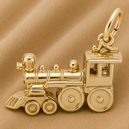 A Rembrandt Charms Train Engine Charm- Gold Plated with a large loop rests on a tan fabric background.