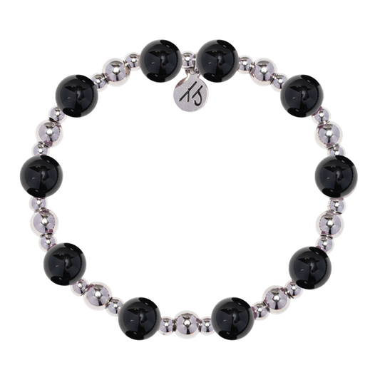 The Day by Day Collection – Onyx Gemstone Bracelet by T Jazelle features alternating large black onyx and smaller metallic silver beads with a round “KS” logo charm, making it perfect gratitude jewelry. Displayed on a white background.