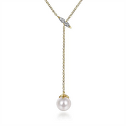 The 14K Yellow Gold Diamond And Pearl Y Knot Necklace by Gabriel & Co features a delicate design with a single white pearl pendant at the end. The chain is adorned with a small diamond-studded leaf near the clasp, creating an elegant and minimalist look.