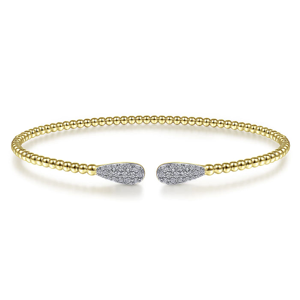 The Gabriel & Co 14K Yellow Gold Bujukan Diamond Teardrops Bangle is an elegant open bracelet from the esteemed Bujukan Collection. Crafted in 14K yellow gold and adorned with a band of small gold beads, this bangle features teardrop-shaped ends encrusted with sparkling diamonds, embodying both minimalistic simplicity and luxurious sophistication.