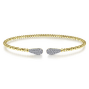 The Gabriel & Co 14K Yellow Gold Bujukan Diamond Teardrops Bangle is an elegant open bracelet from the esteemed Bujukan Collection. Crafted in 14K yellow gold and adorned with a band of small gold beads, this bangle features teardrop-shaped ends encrusted with sparkling diamonds, embodying both minimalistic simplicity and luxurious sophistication.