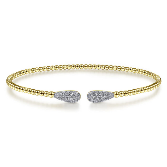 The Gabriel & Co 14K Yellow Gold Bujukan Diamond Teardrops Bangle is an elegant open bracelet from the esteemed Bujukan Collection. Crafted in 14K yellow gold and adorned with a band of small gold beads, this bangle features teardrop-shaped ends encrusted with sparkling diamonds, embodying both minimalistic simplicity and luxurious sophistication.