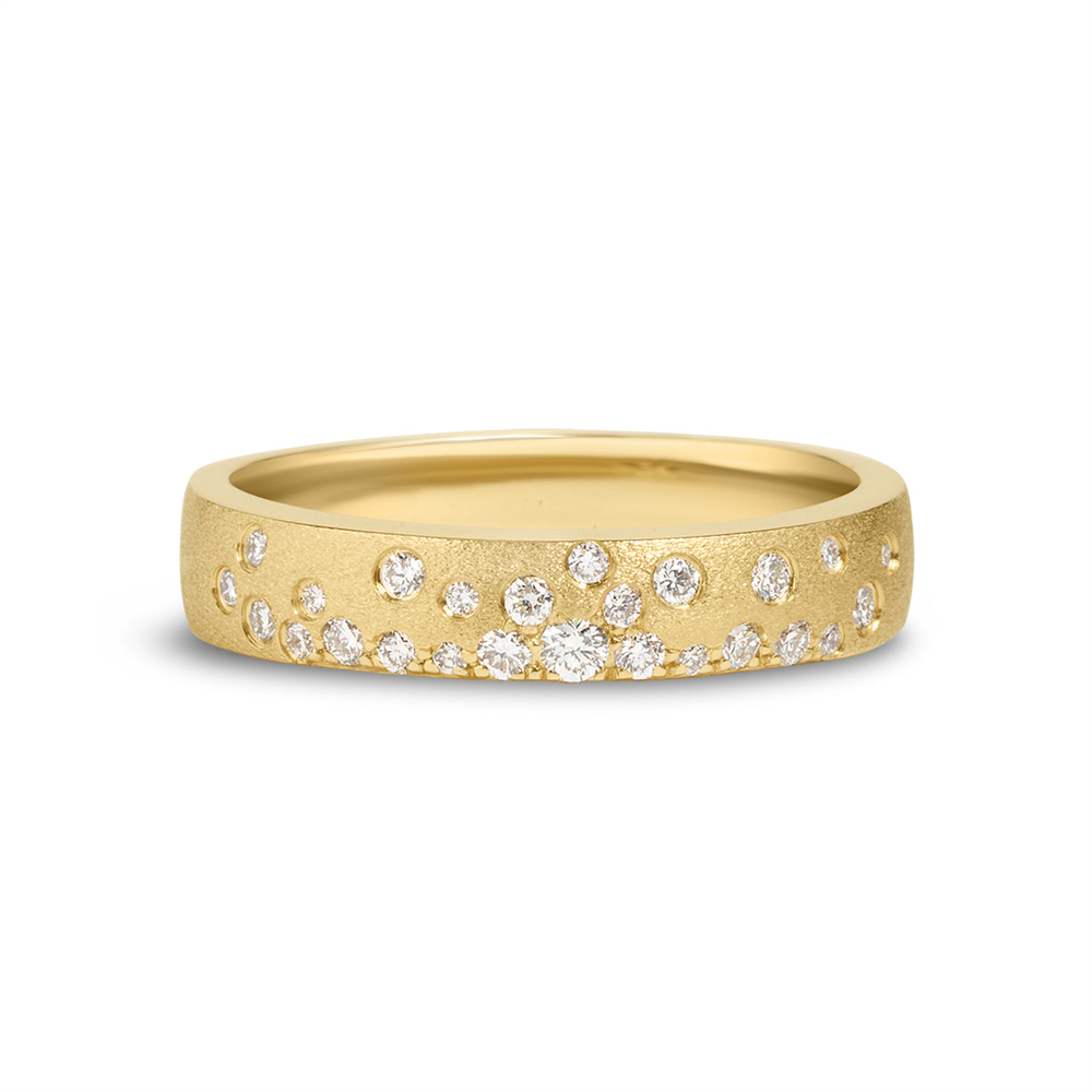 The Diamond Scatter Flush Band by Dilamani is crafted in 14k yellow gold with a luxurious 4.1mm satin finish, showcasing an organic array of small, round diamonds totaling 0.21 carats scattered flush across its matte gold surface.