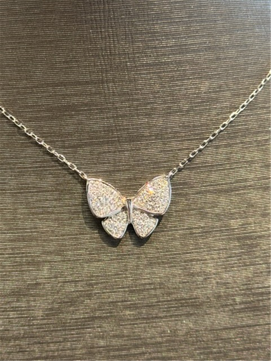 The Ryan Gems Diamond Butterfly Necklace in 14k white gold features a butterfly-shaped pendant with sparkling stones, beautifully showcased against a textured dark background.